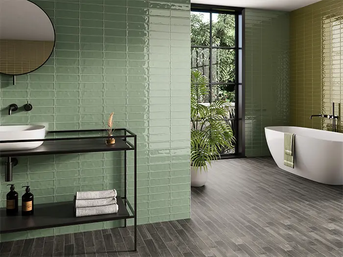 Badkamer met zwarte meubel, spiegel en bad. Twee verschillende kleuren wandtegels en een vloertegel.